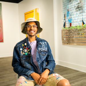 Person sat in a room surrounded by art on the wall