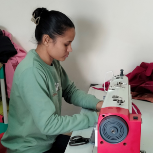 Jyoti sat at a desk using a sewing machine 