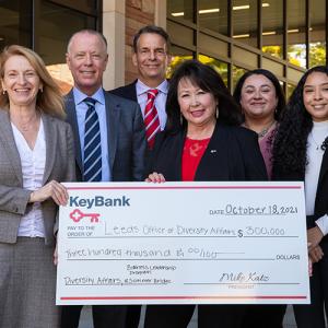 Group of people from Leeds School of Business and KeyBank are holding a check for $300,000. There are 5 women and 3 men in the group.