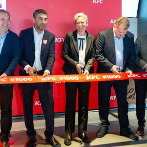 Five people standing behind a ribbon with scissors.