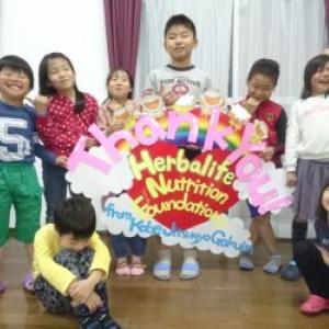 Children around a handmade sign reading Thank You Herbalife Nutrition Foundation