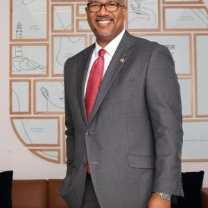 Kala Gibson stood smiling, wearing a grey suit and red tie