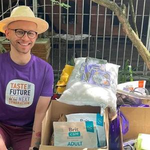 Karol Pacyna sitting next to packed boxes outside.