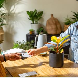 Kat Hernandez holding a card reader for a customer in a plant shop