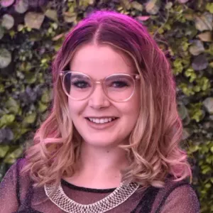 Kate Kirwin, a wall of foliage behind her.