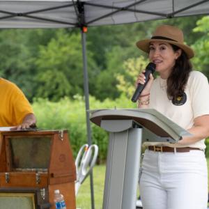 Katherine Dickens speaking at an outdoor podium.
