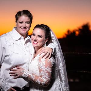 Kathryn and Emily in wedding attire, sunset behind them
