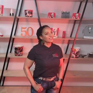 Kedibone Patricia Malatji Lebethe standing in front of a bookcase with KFC awards and memorabilia