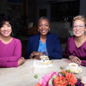 QVC Hosts Leah Williams, Jayne Brown and Rachel Boesing are seated at a table  while on-set at QVC Studios.