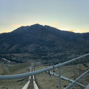 Panoramic view of the valley from a tall building with a safety rail. A road leading down the hill.