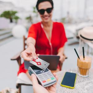 Person at a cafe presenting a KeyBank secured card for payment.