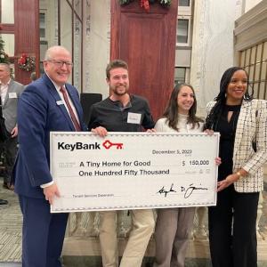 KeyBank and A Tiny Home for Good representatives hold a grant check for $150,000.