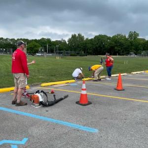 KeyBank volunteers painting barriers in a parking lot for a park.