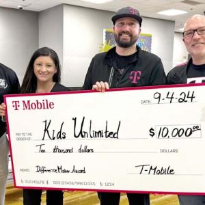 A small group posed with a large check inside a building.