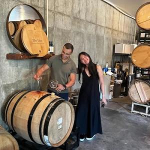 Kim shown in a vineyard with a cask of wine.