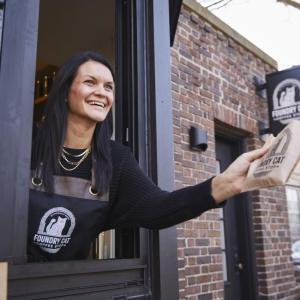 Kimberly Hoffmann leaning out a drive-thru window handing someone an item.