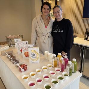 Kimberly Hoffmann and another behind a table with samples of drinks and foods.