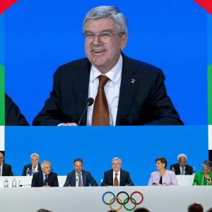 Panel sitting on stage with a large screen overhead