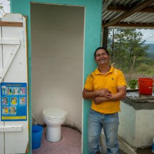 Person smiling next to a new toilet