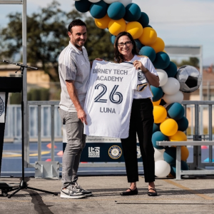 LA Galaxy legend Landon Donovan and an official holding a custom "Birney Tech Academy" jersey.
