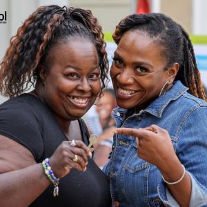 A woman in a denim jacket pointing to Latonya holding a house key