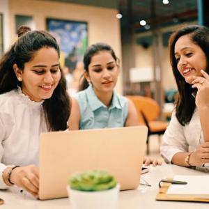 Three people sat at a table looking at a laptop