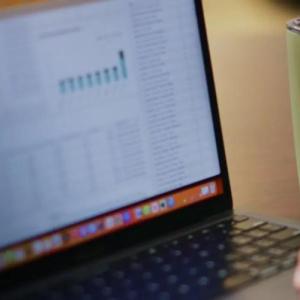 Close up of a person using a laptop, with a Silo travel mug placed to the right-hand side of the laptop