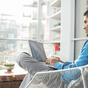 Person wearing headphones, sat on a chair with a laptop on their lap