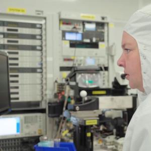 Laura McCarter in a protective suit looking at computer screens.