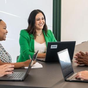 Lesly Luque and team at a conference table, some with open laptops.