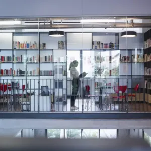 A person behind a glass wall of a library.
