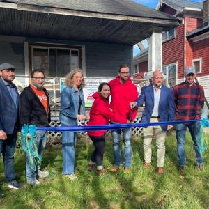 Group of people at a ribbon cutting in front of a home