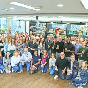 A group of people posed in a room with Bacardi products displayed behind them.