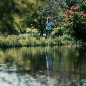 Person stood at the side of a river looking at the trees
