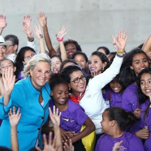 Lucia Prieto in a crowd of children waving to the camera.