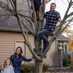 Lynn Moersch with her family outside, a child and adult are sitting in a tree