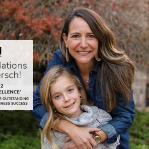 Lynn Moersch hugs a child outside a building with landscaping. "whirlpool- congratulations Lynn Moresch!" on the left.