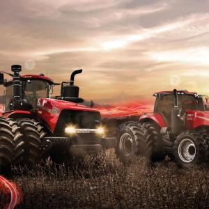 Two red tractors in a farm field, setting sun in the distance and red digital lights behind them.