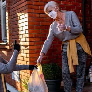 Woman delivering groceries to older woman