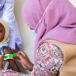 A health worker uses a mid- upper arm circumference (MUAC) band to detect malnutrition. / Photo by Abel Gichuru