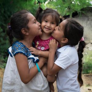 young girls hugging and kissing cheeks