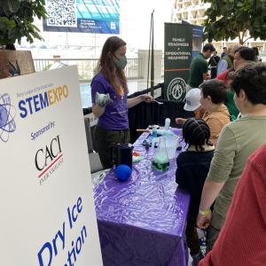 A presenter does a science experiment for onlookers.