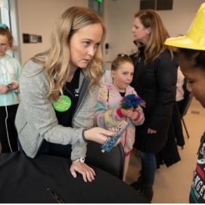 Maddie Eyolfson showing a young child a piece of equipment
