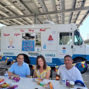 HARMAN people seated at a table with an ice cream truck in the background.