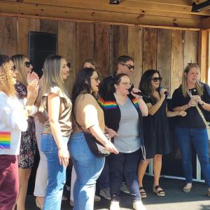 A group of HARMAN people in a circle singing.