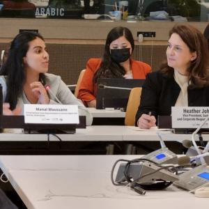 Manal Moussane seated next to Heather Johnson at a long table, other members at a table behind them.
