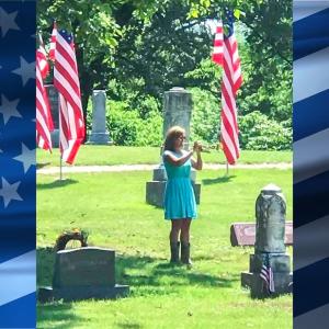 Marianne Masters playing a trumpet in a cemetary.