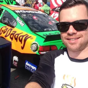Mark shown in front of a GoDaddy sponsored NASCAR.