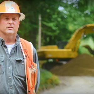 Matt Poppe in hard hat, a large machine behind them.