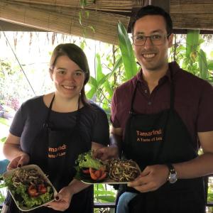 Matthew Sanchez and another in chefs aprons holding a plate of food.